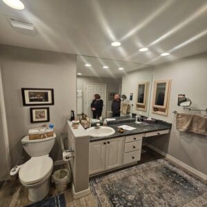 A newly renovated bathroom with a modern vanity, large mirror, and recessed lighting by Jedi Bldrs in Colorado Springs, CO.