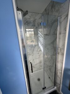 A renovated bathroom showcasing a walk-in shower with grey tiled walls and a stylish mosaic floor by RepairTo Roofing, Renovations & Repairs in Wilmington, DE.