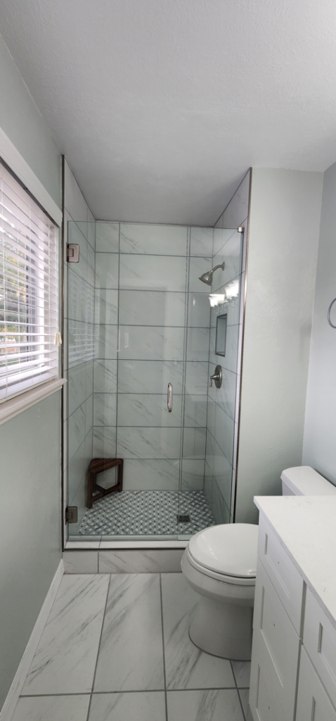 A newly renovated bathroom featuring a modern walk-in shower and tiled floor by Peak2Peak Connect Handyman Services LLC in Arvada, CO.