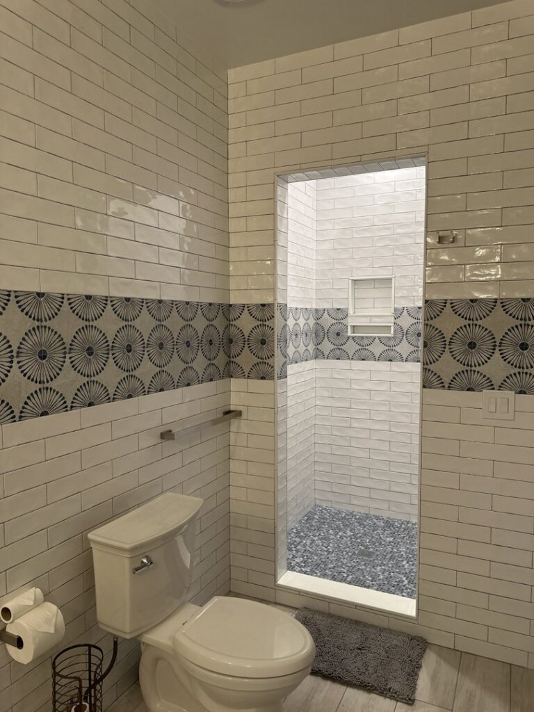 A newly renovated bathroom with a walk-in shower and decorative tiles by Tito's Home Improvement LLC in Stamford, CT.