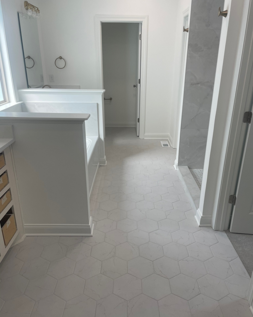 A newly renovated bathroom featuring white hexagon floor tiles, a bathtub, and a modern shower by KACE Construction in Nashville, TN.