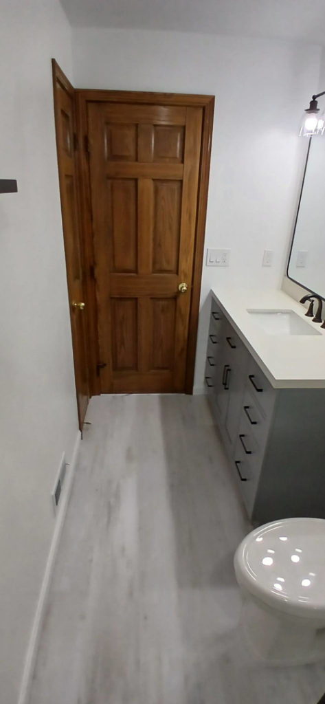 A newly renovated bathroom featuring light grey flooring and a modern vanity by Prime Construction And Flooring in Lorain, OH.