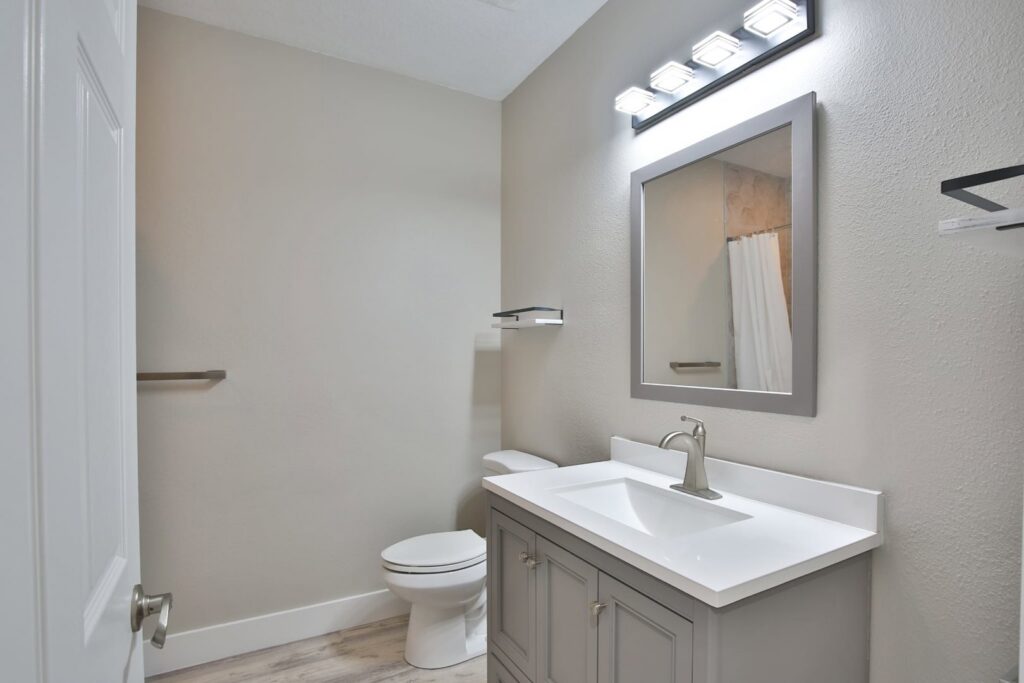 A renovated bathroom featuring a new vanity, sink, mirror, and light fixture by ALKA Construction/ Handyman Services in Layton, UT