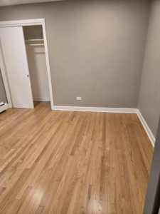 A beautifully renovated bedroom featuring new hardwood floors and a sliding closet door by Specialized Building Services Inc. in Chicago, IL.
