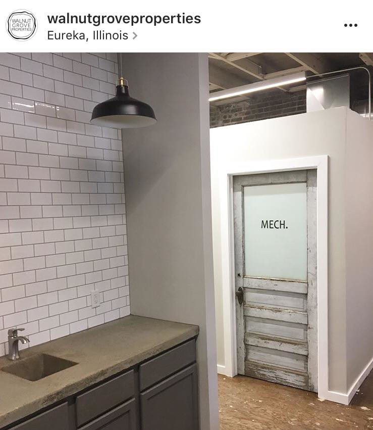 A renovated commercial space featuring a new kitchenette and a rustic 'MECH' door by Failsafe Electric, Inc. in Metamora, IL.