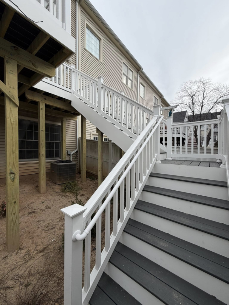 A beautifully renovated deck featuring new white railings and dark steps by Pilgrim Decks and Fence LLC in Elkridge, MD.