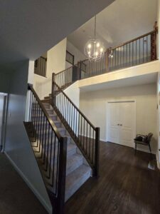 A beautifully renovated entryway and staircase with new balusters and flooring by Benjamin Design - Build in Fishers, IN.