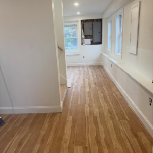 A newly renovated hallway featuring new hardwood flooring and freshly painted white walls by Markos Construction in Cambridge, MA.