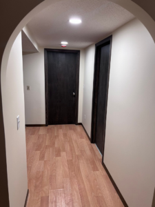 A newly renovated hallway featuring wood-look laminate flooring and dark wood doors and trim by M.R. Renovations, LLC in Maple Grove, MN.