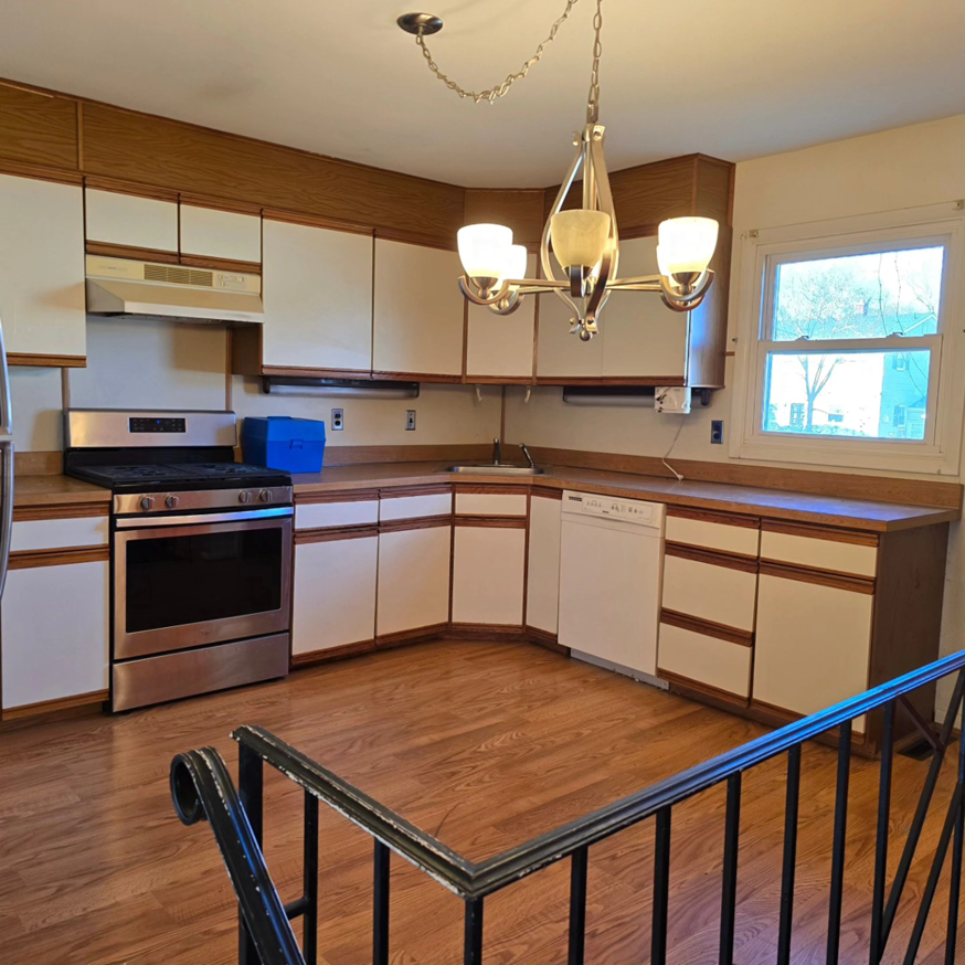 A beautifully renovated kitchen with stainless steel appliances, white cabinets, and wood flooring, completed by 1st State's Finest LLC in Middletown, DE.