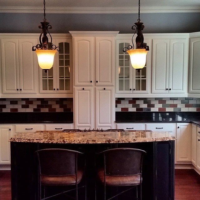 A renovated kitchen featuring white upper cabinets and a dark island, completed by Prime Painting in Charlotte, NC.