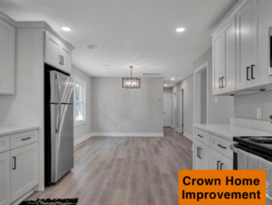 A renovated kitchen and dining area with new flooring, white cabinets, and a modern light fixture by Crown Home Improvements in Charlotte, NC