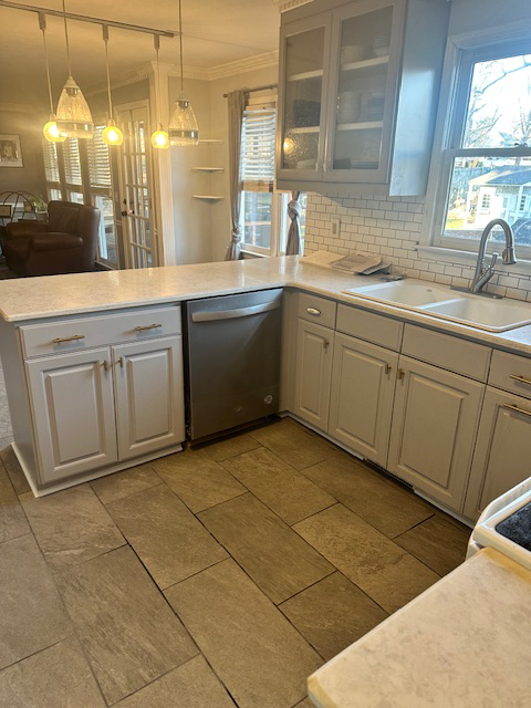 A view of the renovated kitchen showing the new dishwasher, sink, and grey cabinets installed by Bryder Construction in Greenville, SC.