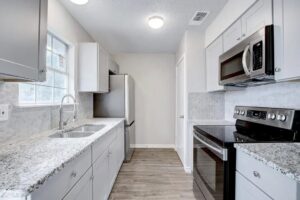 A beautifully renovated kitchen featuring light grey cabinets, granite countertops, and stainless steel appliances by Morin Construction LLC in San Antonio, TX