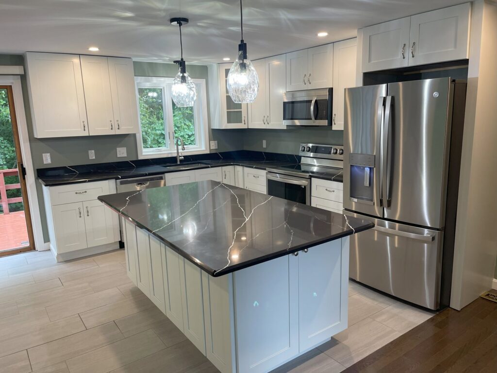 A modern renovated kitchen with an island and white cabinets by Wood Trades LLC in Westport, MA.