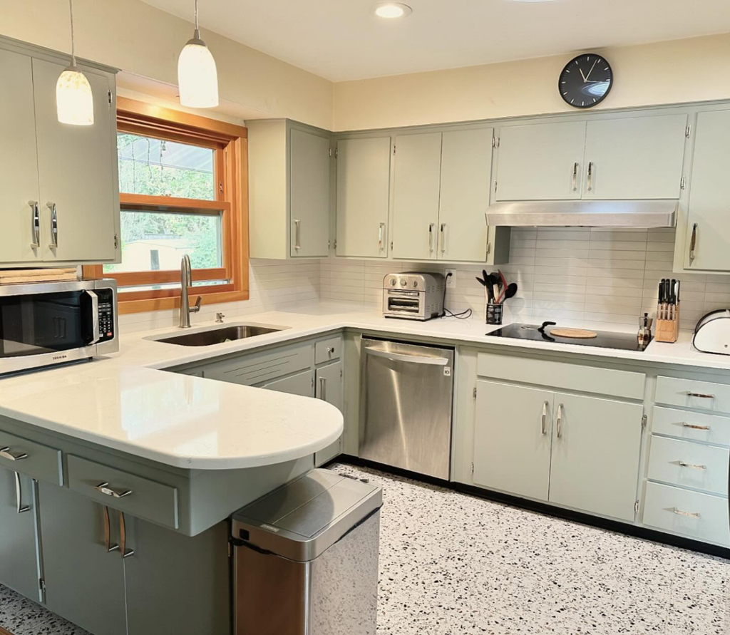 Renovated kitchen with light green cabinets, new white countertops, and backsplash by Cabinet Refinishing Northwest in Beaverton, OR.