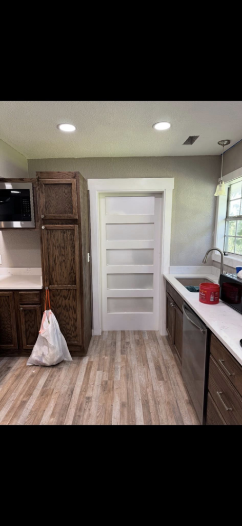 A renovated kitchen featuring new cabinets, countertops, and a modern pantry door by Old Things Created New Handyman Service in Springdale, AR.