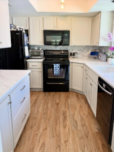 Renovated kitchen featuring white cabinets, new countertops, and backsplash by Cabinet Refinishing Northwest in Beaverton, OR.