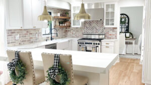 A stunning renovated kitchen featuring white cabinets, a brick backsplash, and a large island by RW Contracting Phila, LLC in Philadelphia, PA.