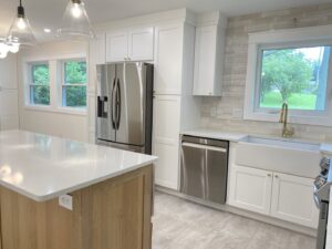 A beautifully renovated kitchen featuring white cabinets, a light wood island, and stainless steel appliances by Westrick Homes in St. Louis, MO.