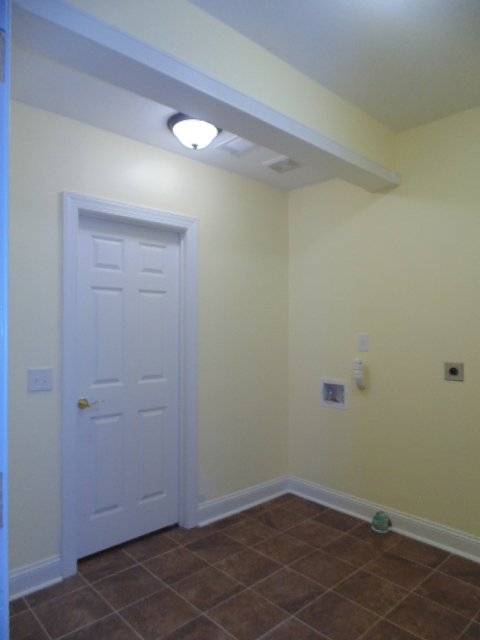 A newly renovated laundry room with tiled flooring and washer/dryer hookups by Pro Renovations Savannah, GA.