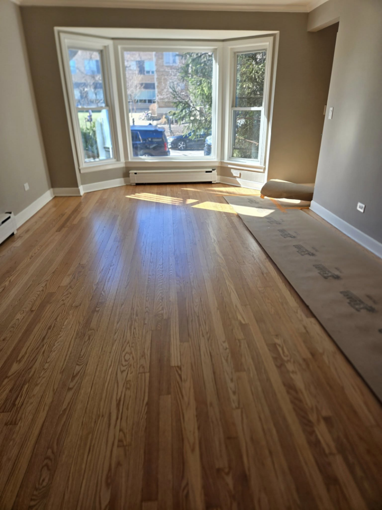 A newly renovated living room with gleaming hardwood floors and a bay window by Specialized Building Services Inc. in Chicago, IL.