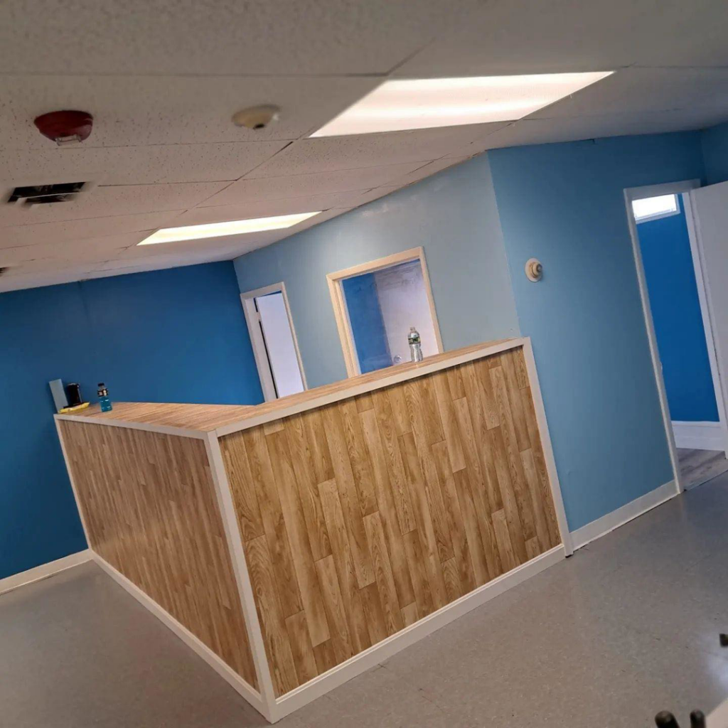 A newly renovated office reception area with blue walls and a wooden desk, completed by Kznconstructionllc in Johnston, RI.