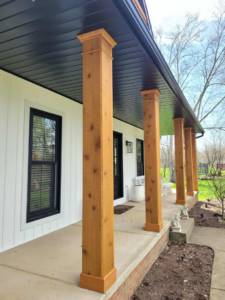 A beautifully renovated porch with new wooden columns and white siding by 1st Choice Windows in Canton, OH.