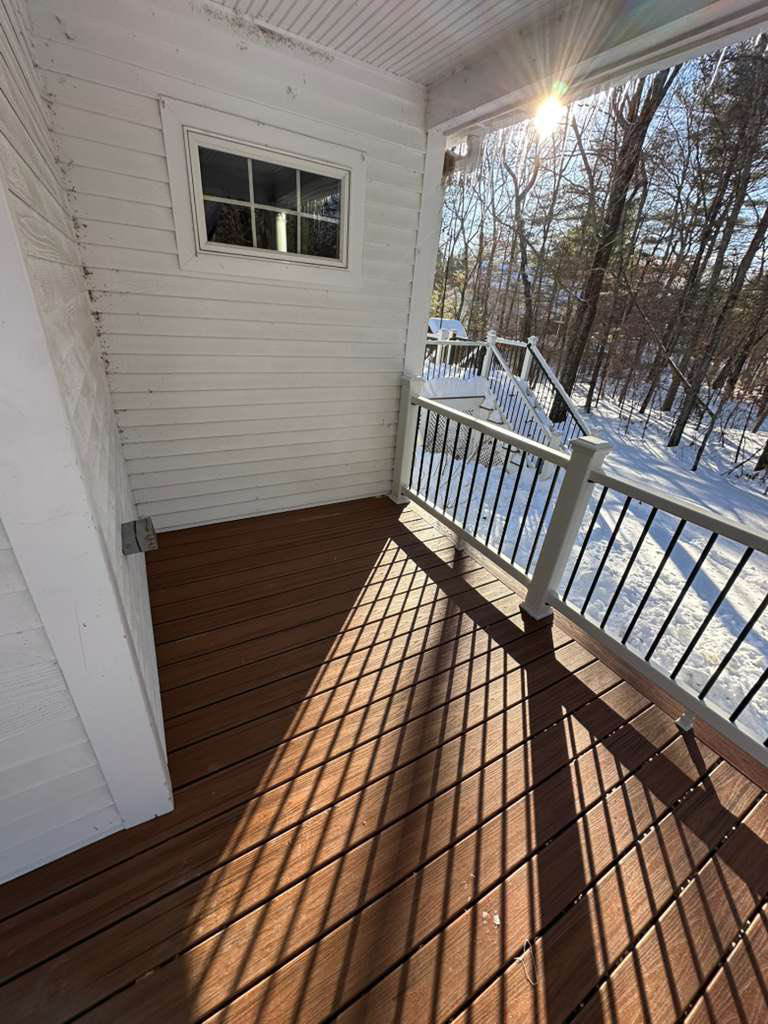 A renovated porch with new composite decking and white railings, demonstrating quality craftsmanship by Remodel or Renew Home Improvement in Worcester, MA.