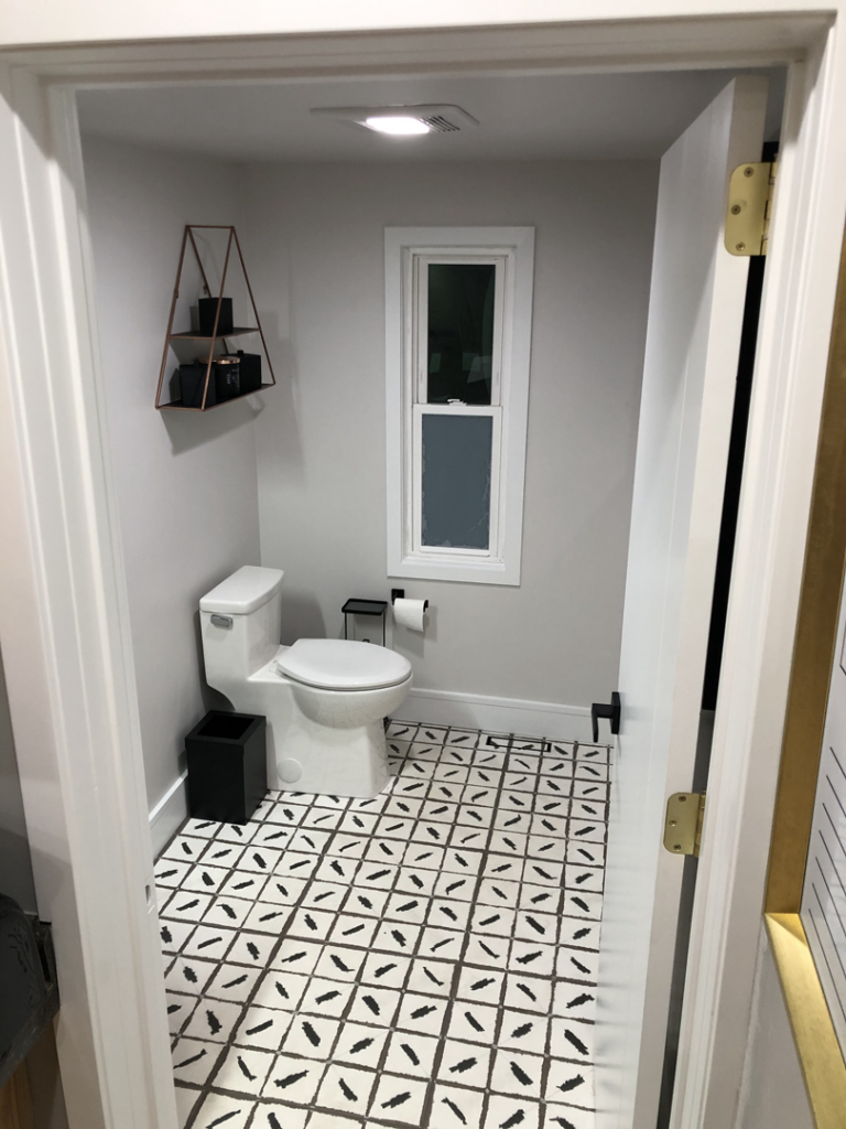 A newly renovated powder room with patterned floor tiles and a white toilet by Elde Contracting in Saint Paul, MN.
