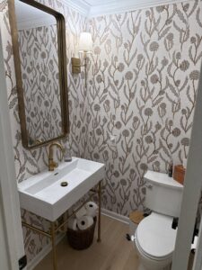 Renovated powder room with a modern vanity, toilet, and patterned wallpaper by HomePro Improvements, Roswell, GA.