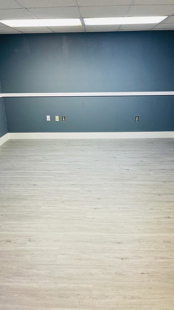 A newly renovated room featuring dark blue walls, white trim, and light wood-look laminate flooring by SD Masters in Miami, FL.