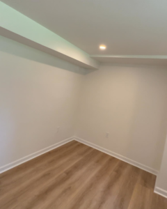 A corner of a renovated room with new flooring and recessed lighting, showcasing work by Under The Wire Renovations in Atlanta, GA.