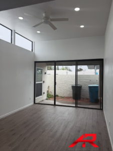 A recently renovated room featuring new wood-look flooring, a modern ceiling fan, and large sliding glass doors by AGM Remodeling LLC in Scottsdale, AZ.