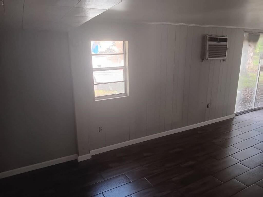 A newly renovated room with dark tile flooring, painted walls, and baseboards by Joel's flooring & Handyman services in Roy, UT.