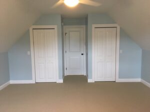 A renovated room featuring light blue walls and new bi-fold closet doors by Casco Bay Construction Services, LLC in South Portland, ME.