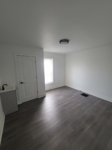 A renovated room with dark wood-style flooring and a small sink unit, completed by Modern Image Construction LLC in El Paso, TX.