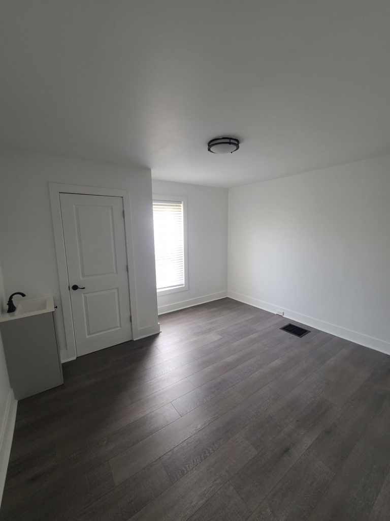 A renovated room with dark wood-style flooring and a small sink unit, completed by Modern Image Construction LLC in El Paso, TX.