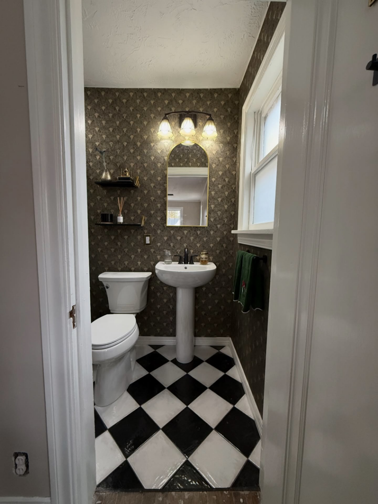 The entrance view of a newly renovated small bathroom with black and white tiled floor by Waking Up Construction in Oklahoma City, OK