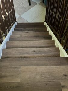 A renovated staircase with dark wood-look treads and ornate metal railings, a project by SD Masters in Miami, FL.