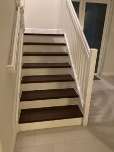 A beautifully renovated staircase featuring dark wood-look treads and white railings by SD Masters in Miami, FL.