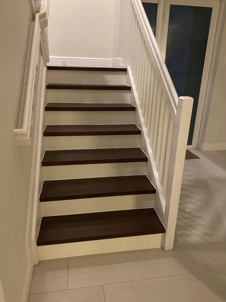 A beautifully renovated staircase featuring dark wood-look treads and white railings by SD Masters in Miami, FL.