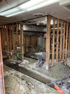 A renovation site showing exposed framing, floor trenches, and construction debris by JB Renovations in Houston, TX.