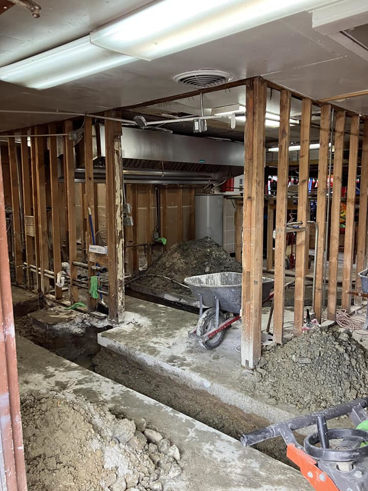 A renovation site showing exposed framing, floor trenches, and construction debris by JB Renovations in Houston, TX.