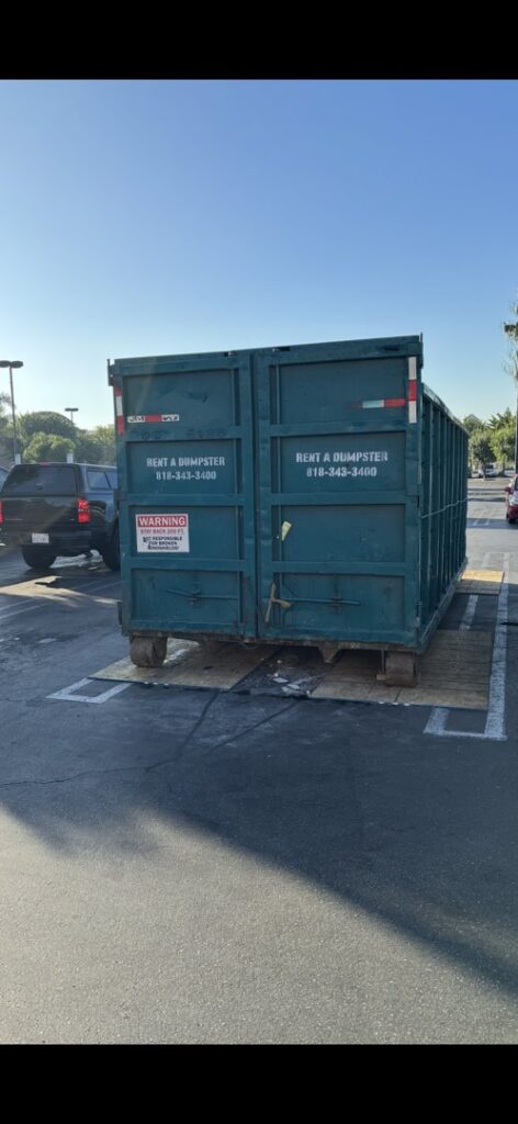 A Quality Bin Inc. dumpster with 'Rent a Dumpster' visible, placed in a parking lot in Los Angeles, CA.