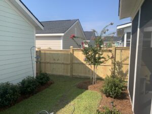 A newly installed wooden privacy fence enhancing a residential backyard with landscaping by Frontline Fencing LLC in Summerville, SC.