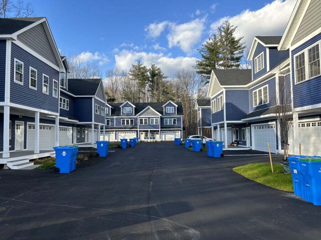 Residential trash and recycling bins lined up in a townhouse community by Champion Waste Services in Londonderry, NH.