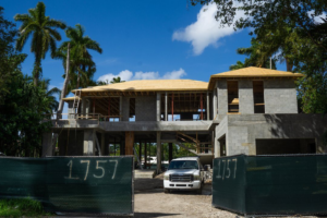 The exterior of a residential home under construction, featuring concrete block walls and roof framing by Intelligent Construction Inc. in Miami, FL.