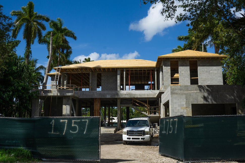 The exterior of a residential home under construction, featuring concrete block walls and roof framing by Intelligent Construction Inc. in Miami, FL.