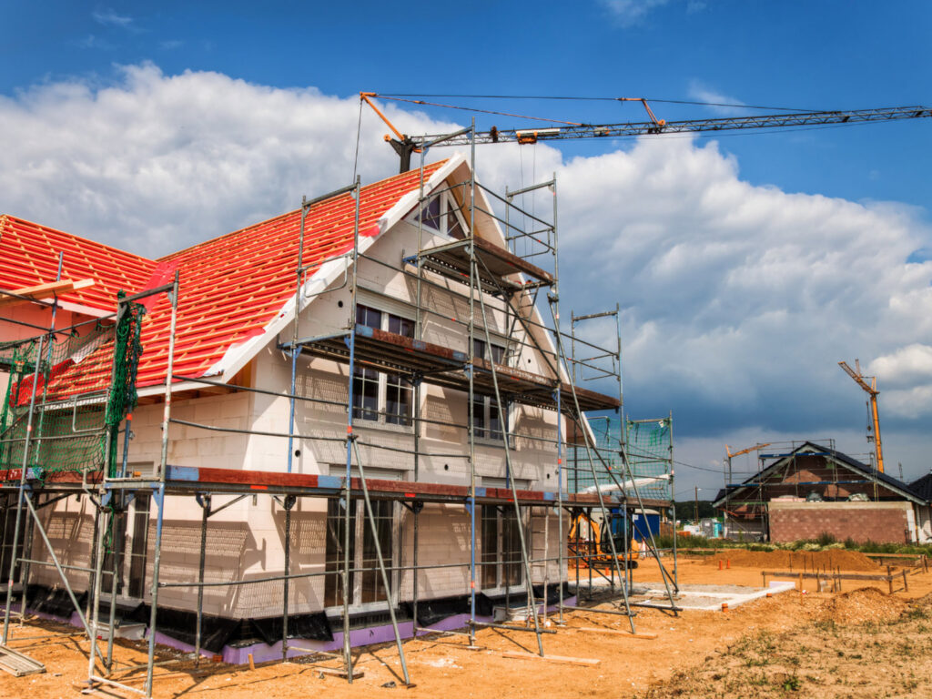 Residential house under construction with scaffolding and a red roof by Trident General Contracting in Plano, TX.